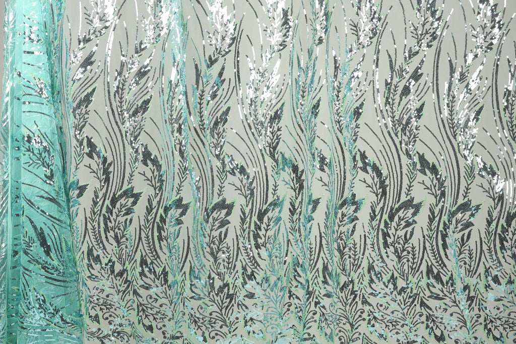 a close-up view of a fabric with a repeating pattern of green and black leaf-like designs. The pattern is intricate and detailed, creating a visually striking and textured appearance.