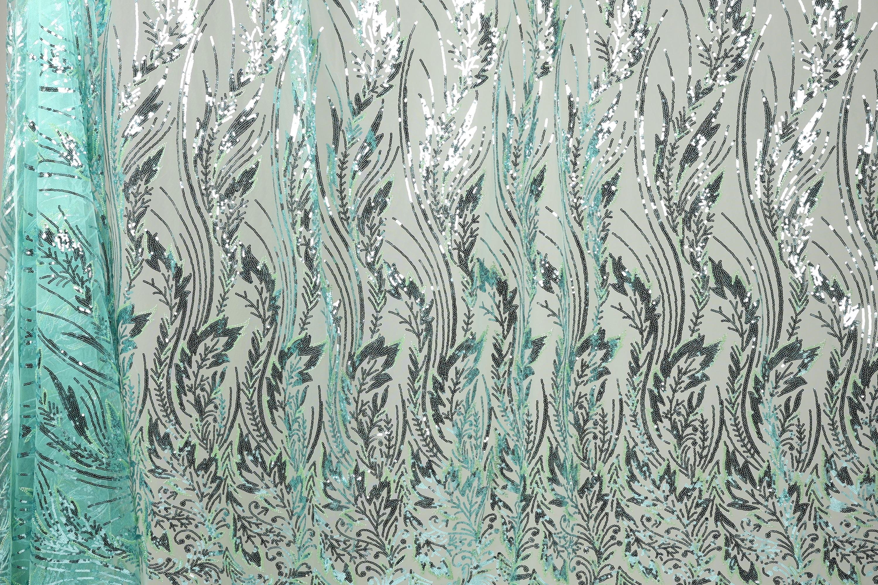 a close-up view of a fabric with a repeating pattern of green and black leaf-like designs. The pattern is intricate and detailed, creating a visually striking and textured appearance.
