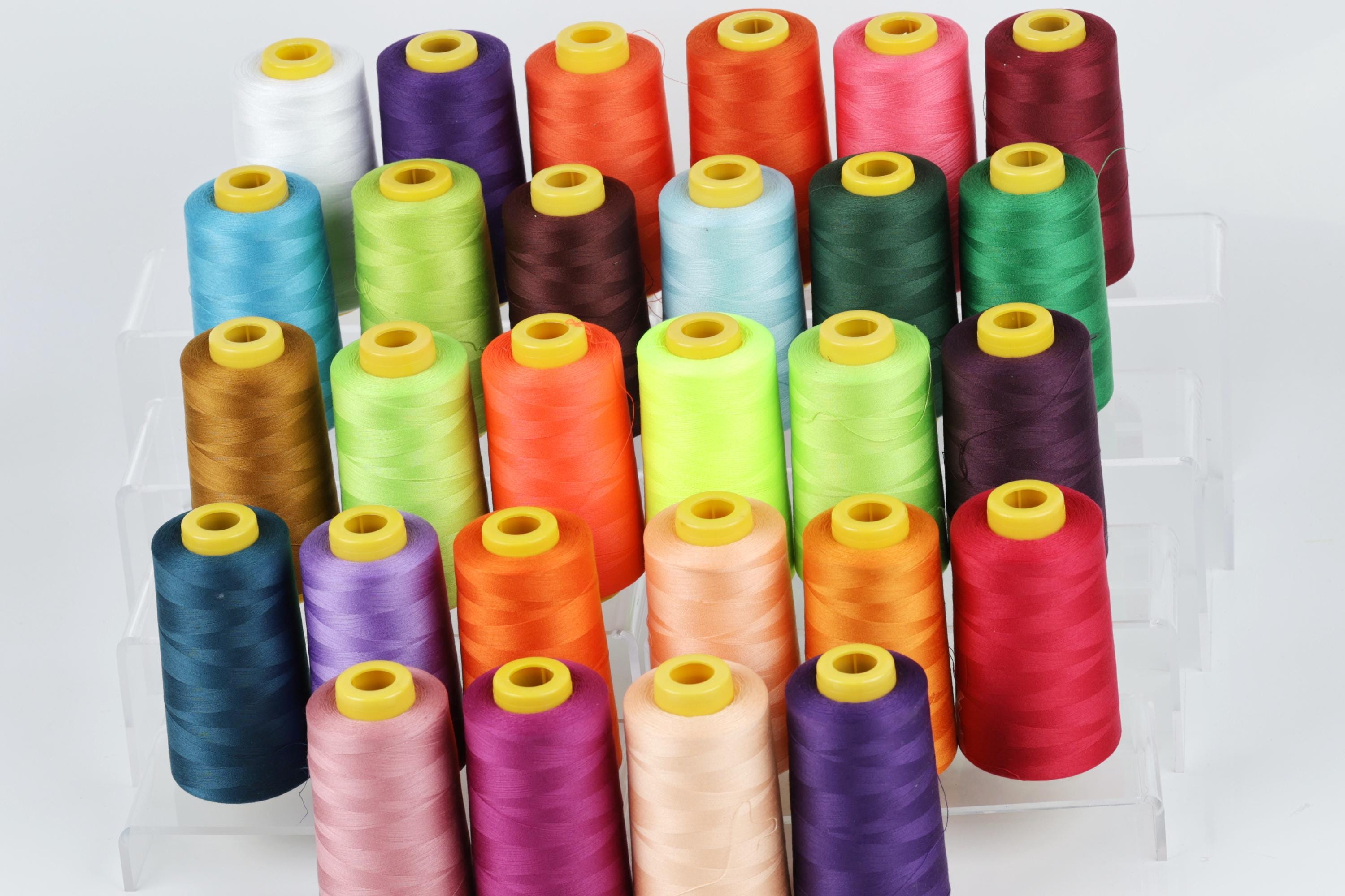 a collection of colorful spools of thread arranged in rows on a white background.