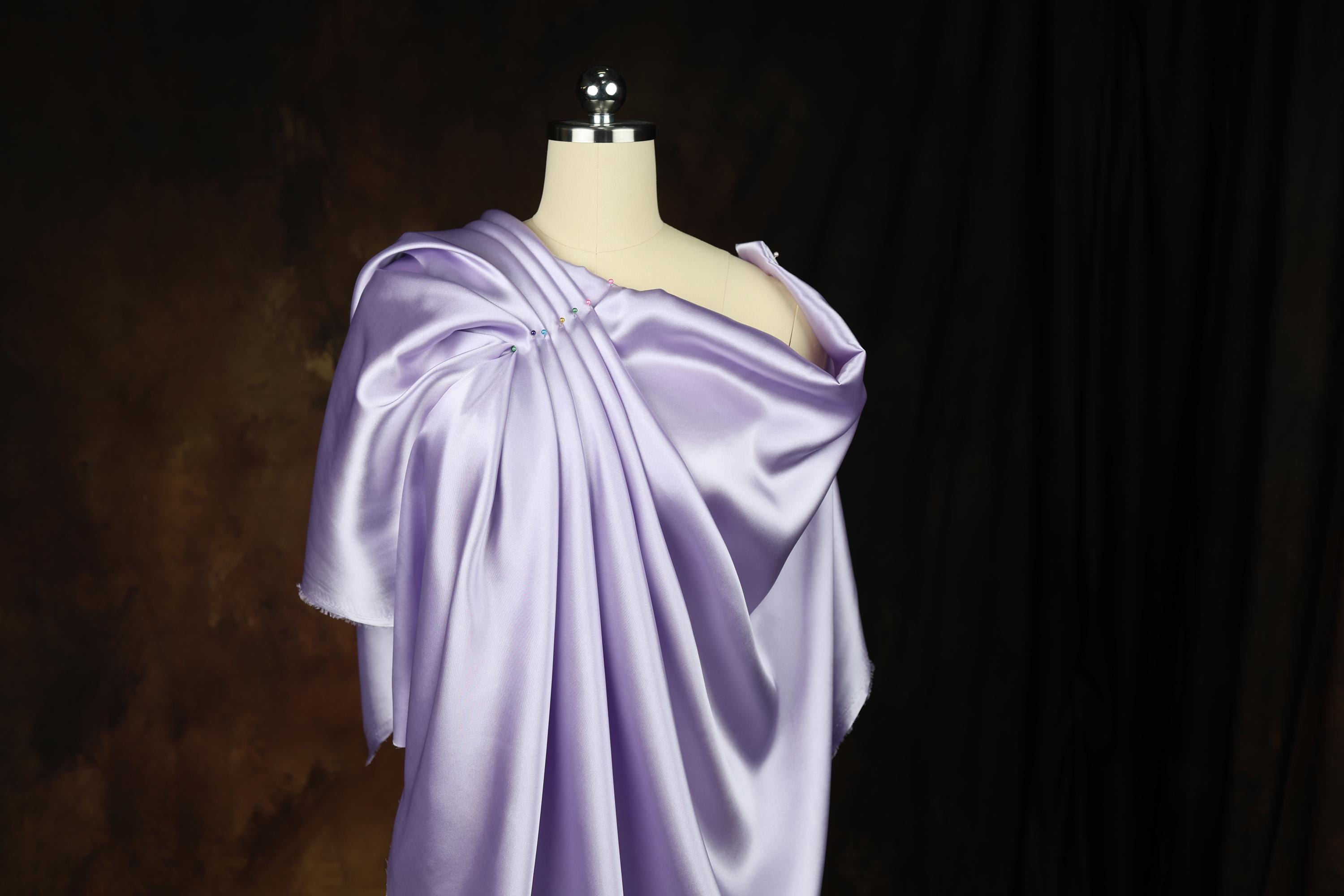 a mannequin dressed in a purple dress with a cape