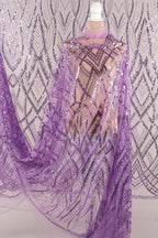a mannequin wearing a purple sequin dress with a sheer overlay. The dress has a pattern of purple and silver sequins, creating a visually striking and elegant design.