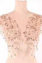 a close-up view of a delicate, beige-colored fabric adorned with intricate gold and brown sequin details.