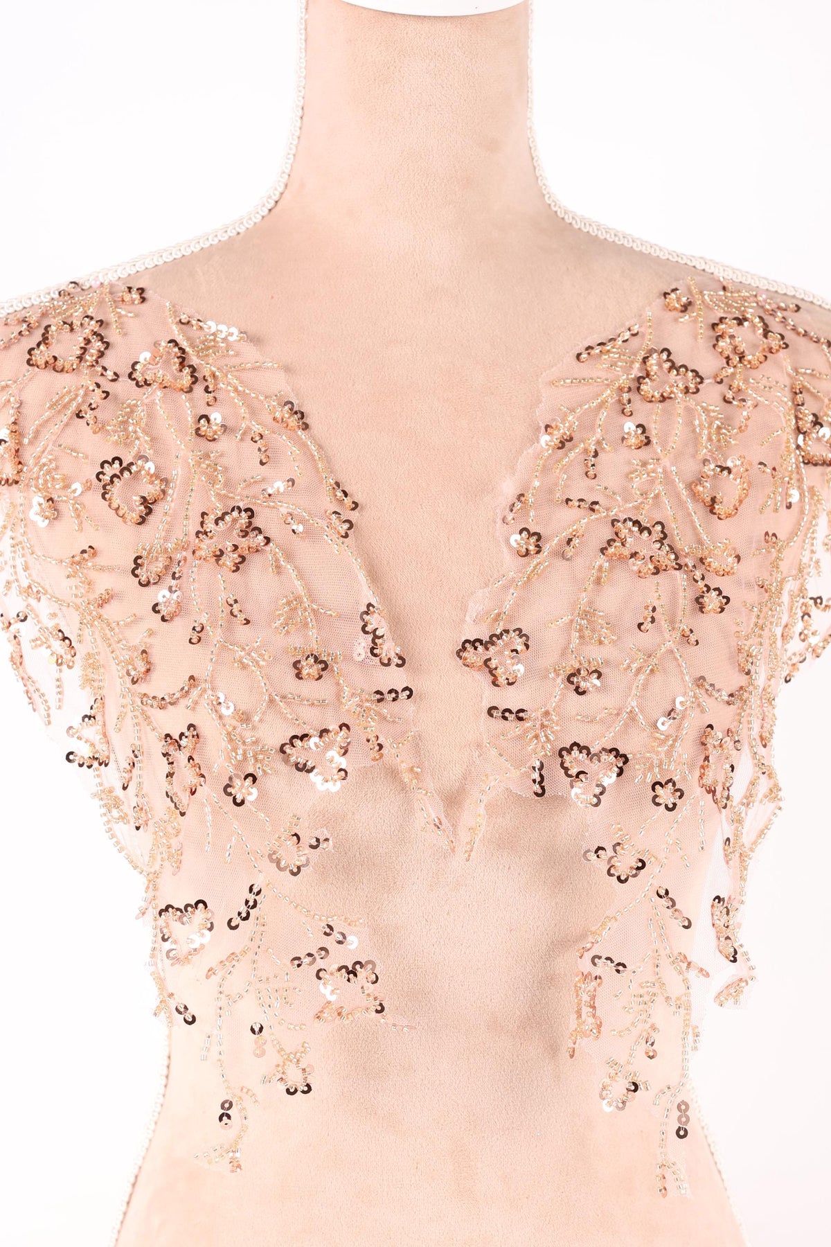 a close-up view of a delicate, beige-colored fabric adorned with intricate gold and brown sequin details.