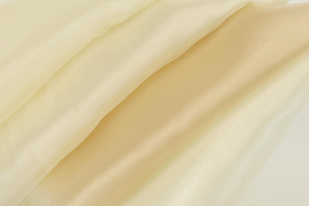 The image is a close-up of a fabric with a soft, flowing texture in shades of yellow and beige.