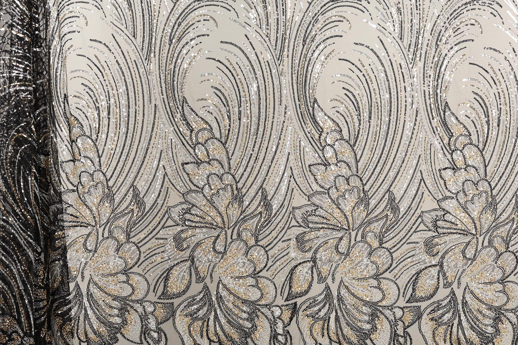 a close-up view of a fabric with a repeating floral pattern in shades of black and gold. The pattern consists of stylized flowers and leaves, creating a visually striking and intricate design. The fabric appears to be made of a shiny, metallic material, which adds a unique texture and visual interest to the overall composition.