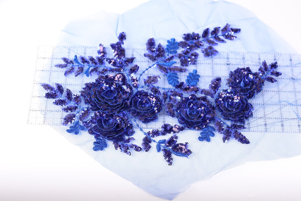 a close-up view of a blue sequin flower design on a piece of fabric.