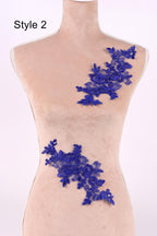 A mannequin with a light-colored torso, wearing a blue floral lace piece on the right side of the torso.
