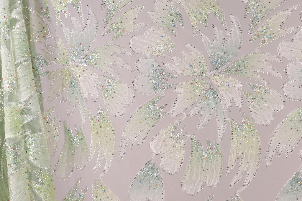 a close-up view of a fabric with a floral pattern, adorned with small, multicolored beads or sequins that create a sparkling effect.