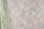 a close-up view of a fabric with a floral pattern, adorned with small, multicolored beads or sequins that create a sparkling effect.