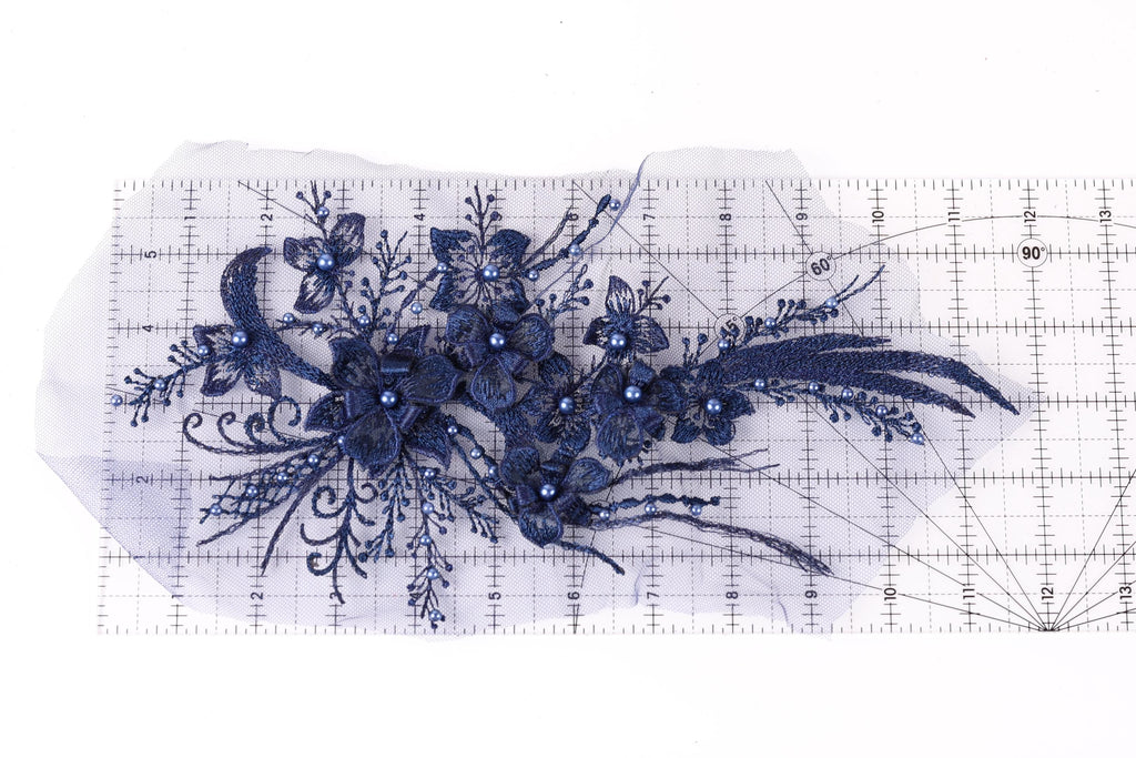 a close-up view of a delicate blue floral embroidery piece, with intricate details and a vibrant blue color.