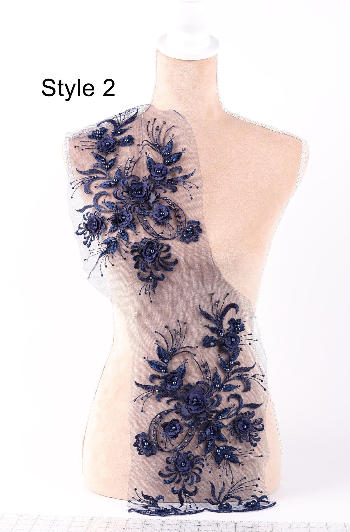 A mannequin wearing a dress with a floral pattern on the shoulder and a sheer overlay.