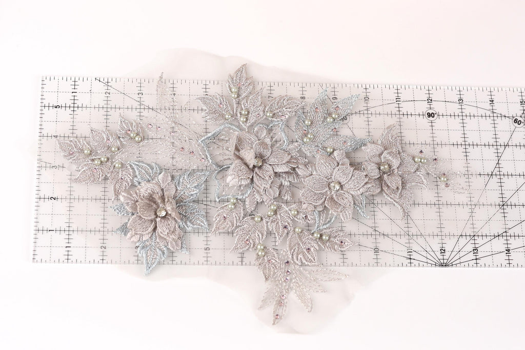 a delicate floral embroidery with a ruler placed on a white background.