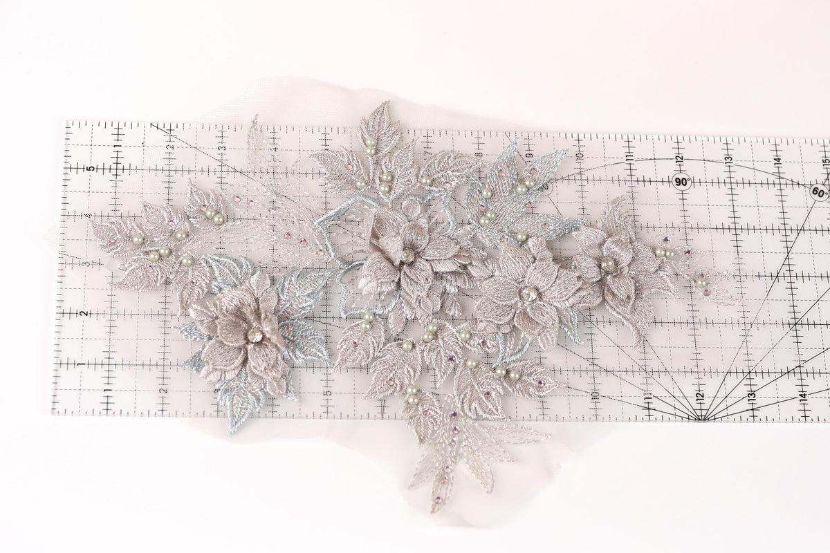 a delicate floral embroidery with a ruler placed on a white background.