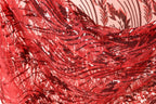 a close-up view of a red sequin fabric with a floral pattern. The fabric appears to be made of a shiny, shiny material with a textured, woven appearance.