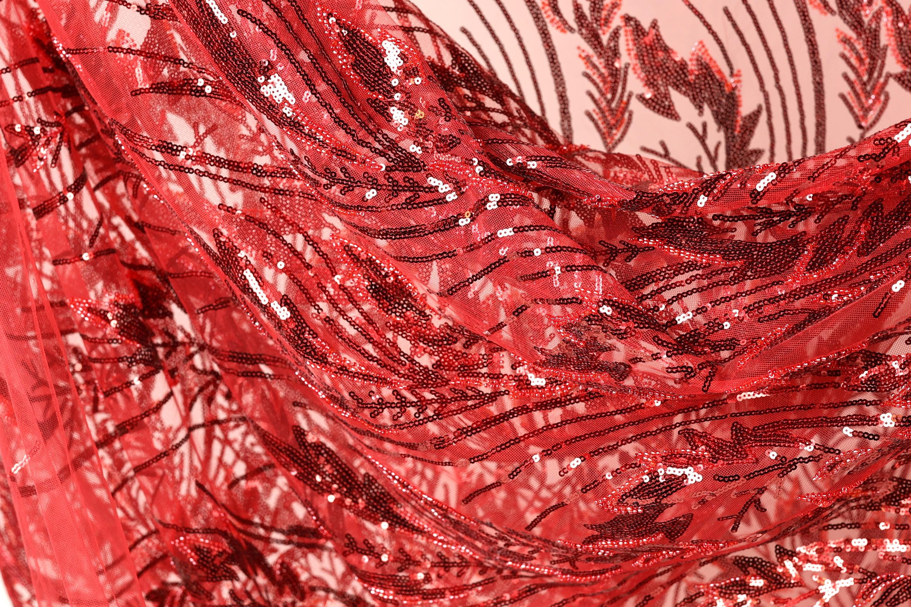 a close-up view of a red sequin fabric with a floral pattern. The fabric appears to be made of a shiny, shiny material with a textured, woven appearance.