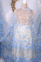 A mannequin wearing a white dress with a sheer blue floral fabric draped over it.