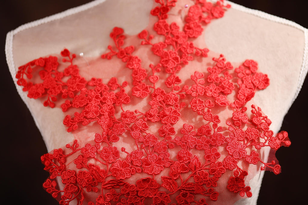 A close-up view of a mannequin torso wearing a red lace dress with a floral pattern.