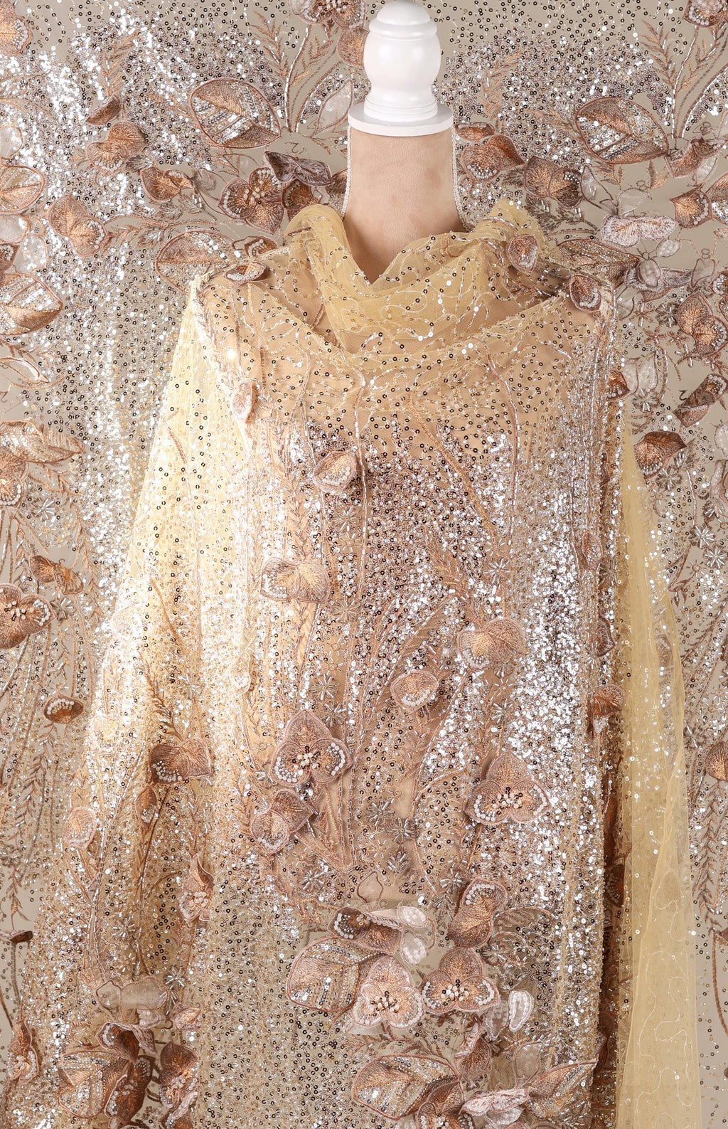 a mannequin wearing a gold and beige sequined dress with a floral pattern.
