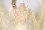 A mannequin wearing a yellow lace dress with a floral pattern.