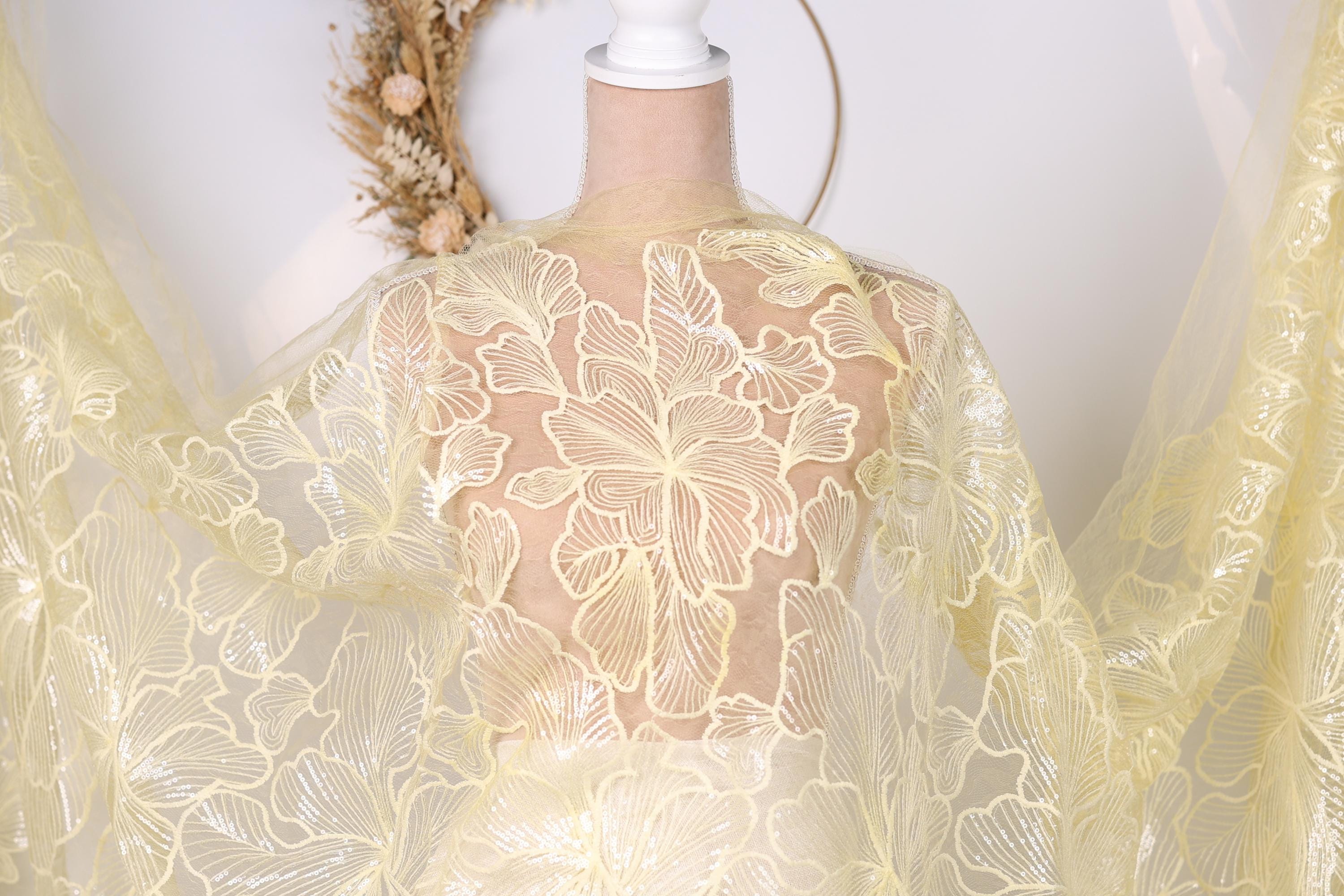 A mannequin wearing a yellow lace dress with a floral pattern.