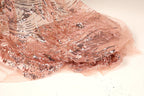 a close-up view of a delicate, pink sequined fabric with a floral pattern. The fabric appears to be made of sheer material, giving it a soft and delicate appearance.