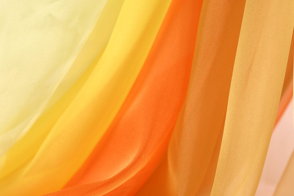 The image is a close-up of a fabric with a vibrant yellow, orange, and red gradient, creating a visually striking and colorful effect.
