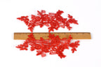 a collection of red embroidered or crocheted fabric pieces, with a ruler placed between them to provide a sense of scale.