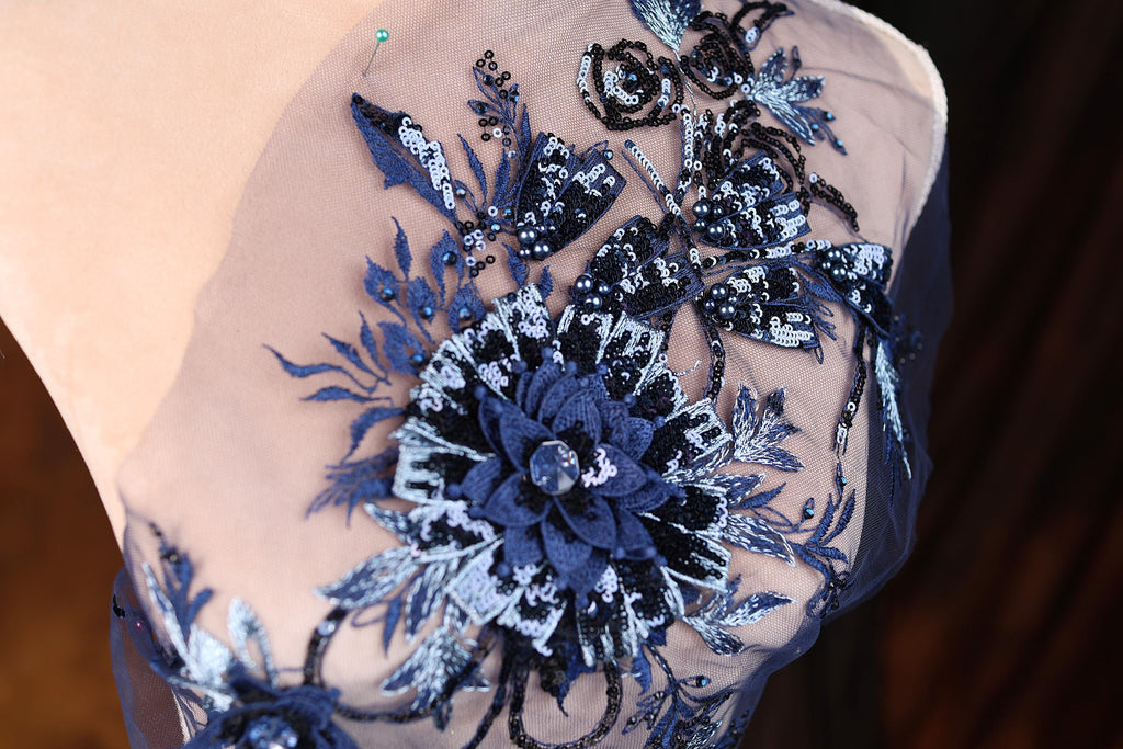 a close-up view of a delicate, intricately embroidered fabric with a blue and white floral design.