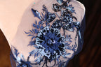 a close-up view of a delicate, intricately embroidered fabric with a blue and white floral design.