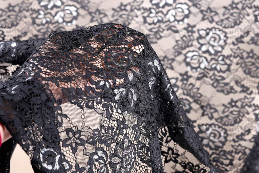 A close-up view of a black lace fabric with intricate floral patterns.