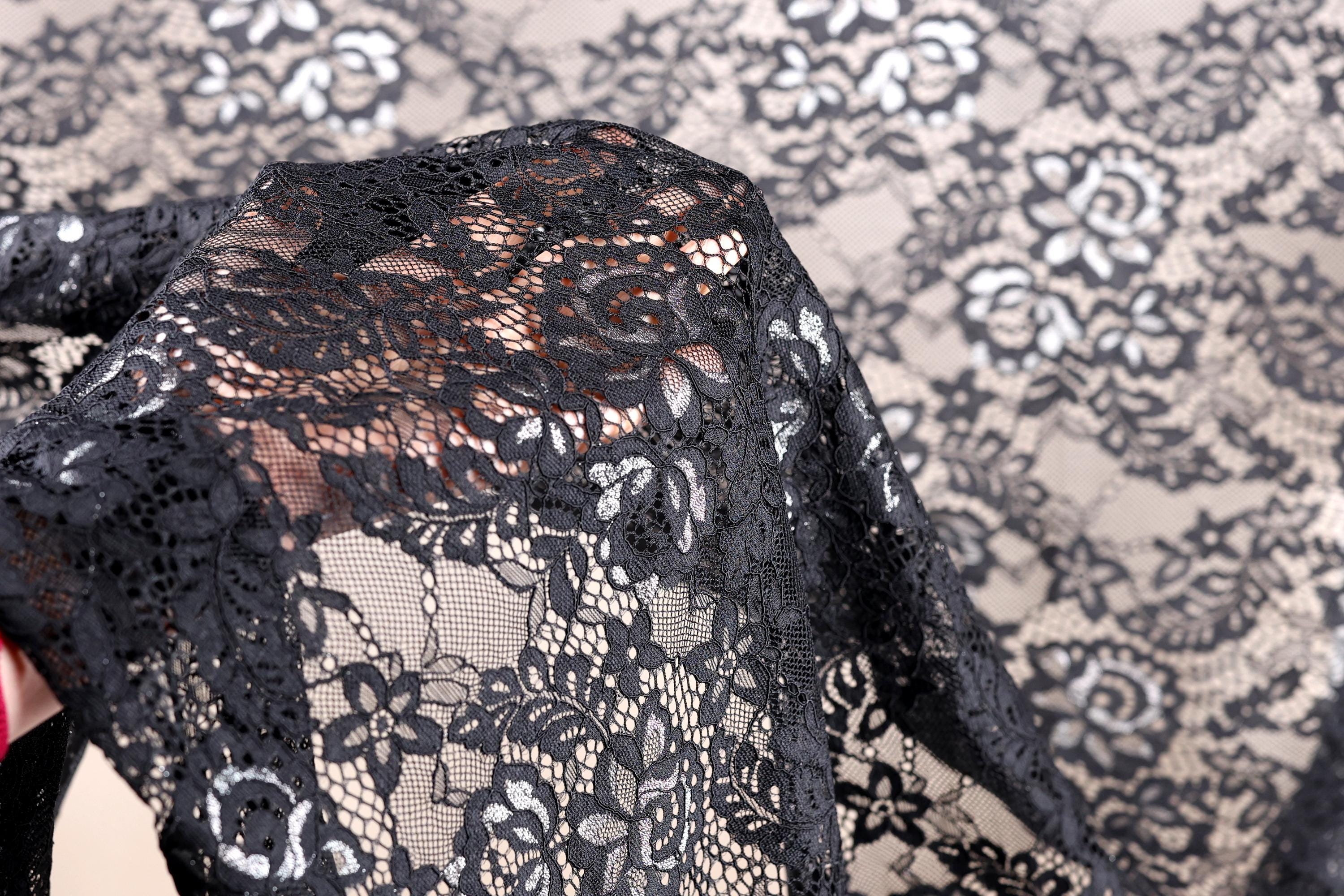 A close-up view of a black lace fabric with intricate floral patterns.