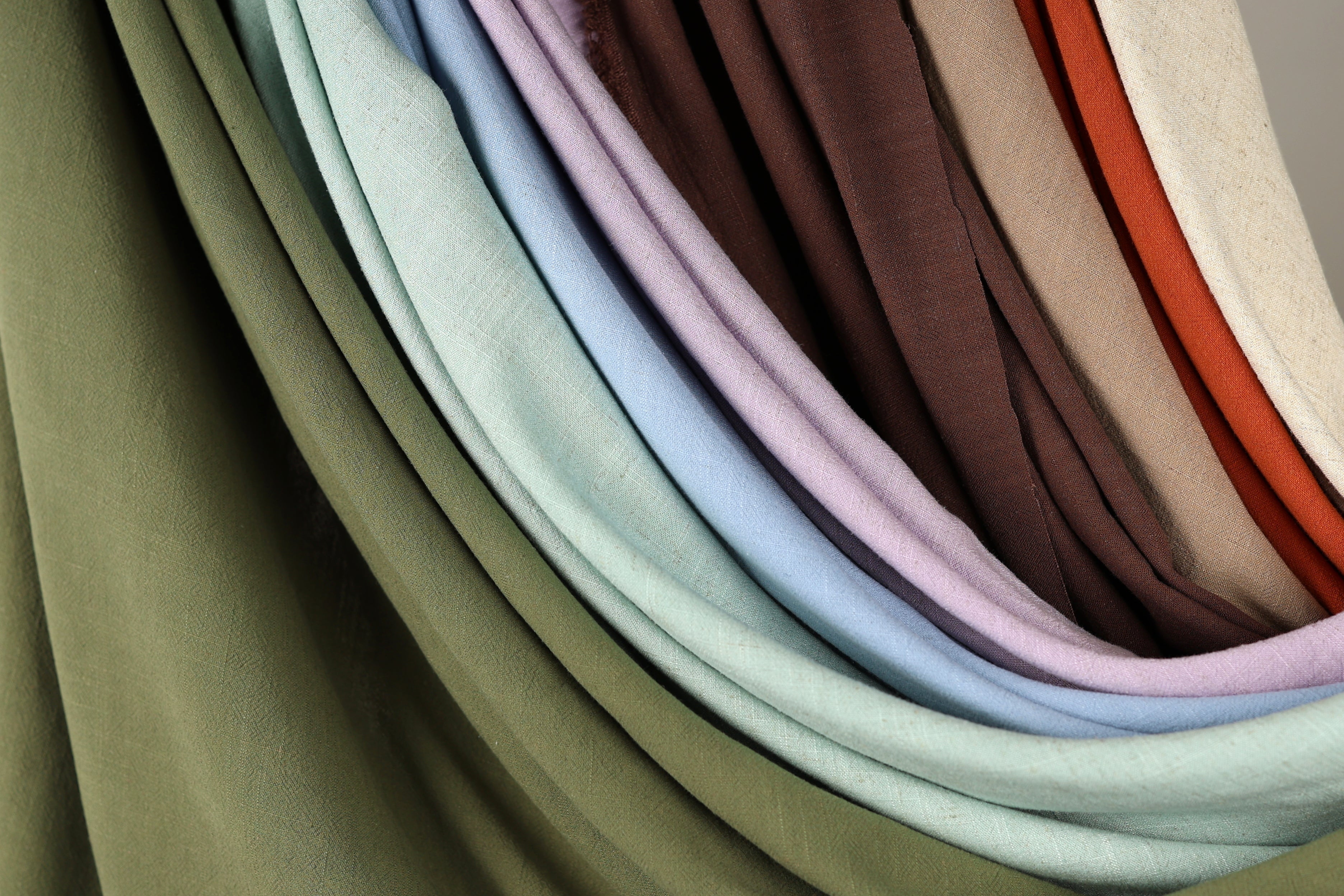 A collection of colorful fabric swatches, including various shades of green, blue, purple, and brown, arranged in a visually appealing manner.