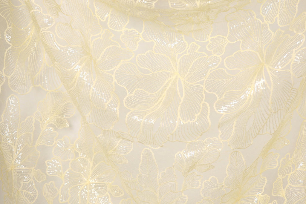 a close-up view of a fabric with a delicate, intricate floral pattern in a pale yellow color. The pattern consists of numerous small, overlapping flowers and leaves, creating a visually appealing and textured appearance.