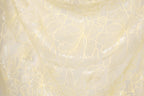 a close-up view of a fabric with a delicate, intricate floral pattern in a pale yellow color. The pattern consists of numerous small, overlapping flowers and leaves, creating a visually appealing and textured appearance.