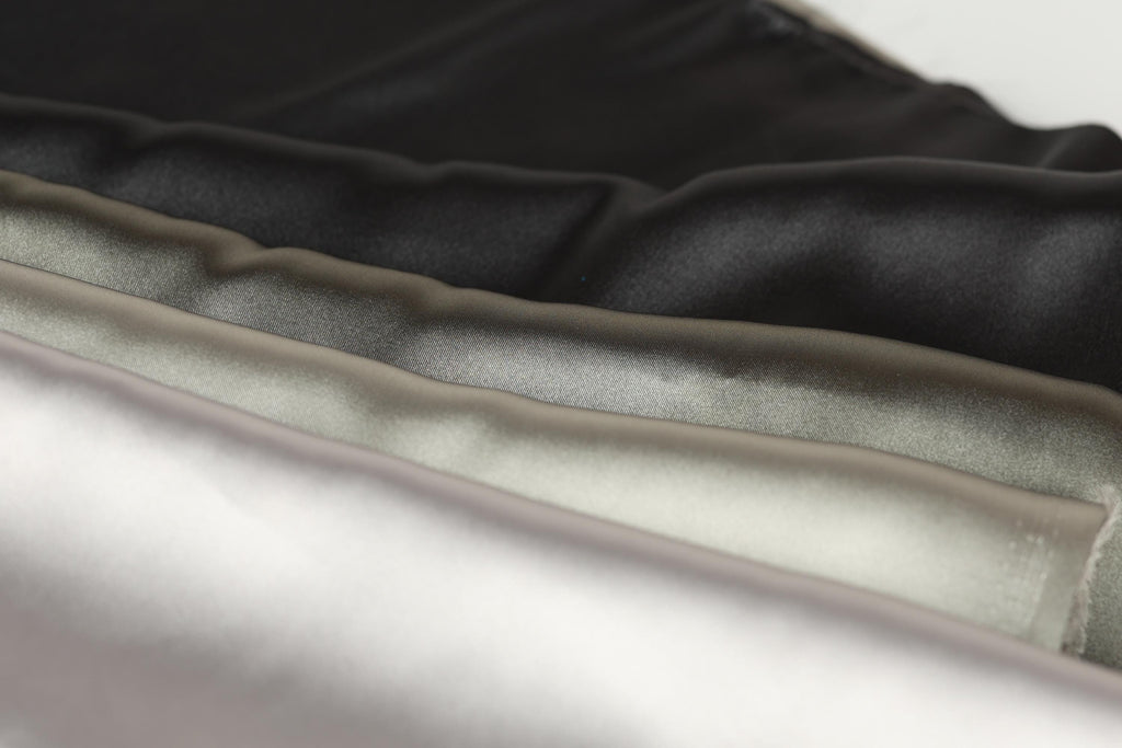 A close-up image of a collection of fabric swatches in various shades of black, gray, and white.