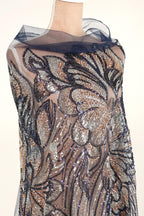 a mannequin wearing a dress with a sheer, sheer-like fabric that is covered in a floral pattern. The dress appears to be made of sequins and has a blue and black color scheme.