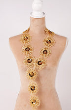 A mannequin wearing a gold necklace with multiple flower-shaped pendants.