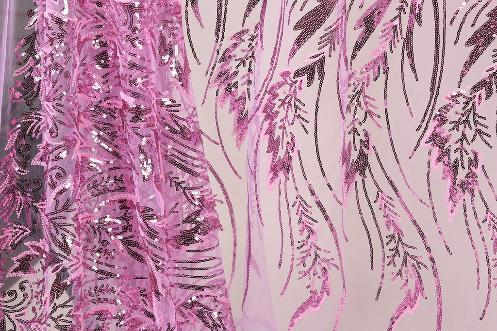 a close-up view of a fabric with a pink and black sequin pattern. The fabric appears to be a sheer material, with the pink sequins creating a floral or leaf-like design. The pattern is intricate and detailed, with the pink sequins adding a vibrant touch to the overall appearance of the fabric.