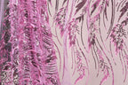 a close-up view of a fabric with a pink and black sequin pattern. The fabric appears to be a sheer material, with the pink sequins creating a floral or leaf-like design. The pattern is intricate and detailed, with the pink sequins adding a vibrant touch to the overall appearance of the fabric.