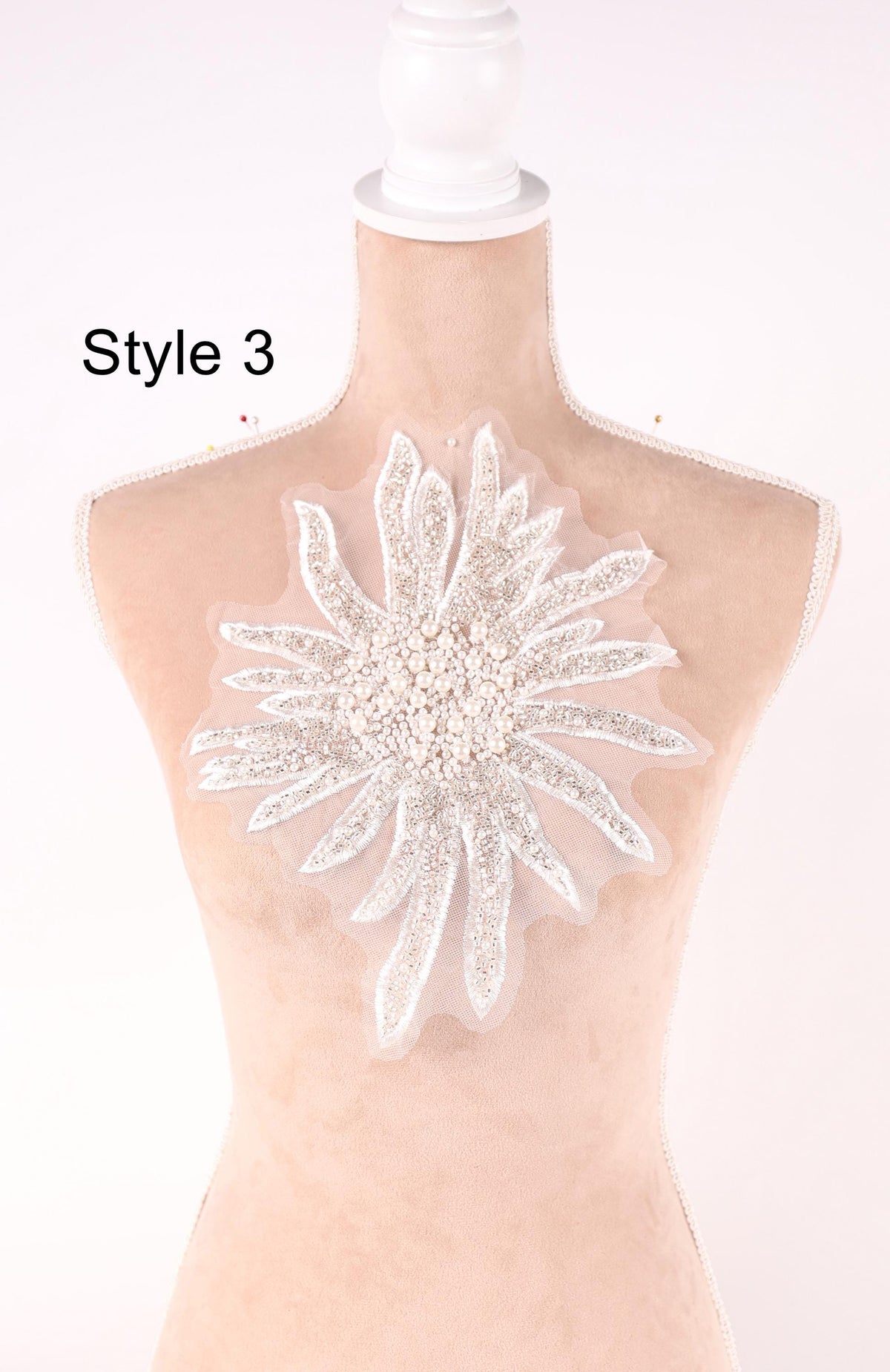 A mannequin with a large, intricate white flower-shaped embellishment on its bust.