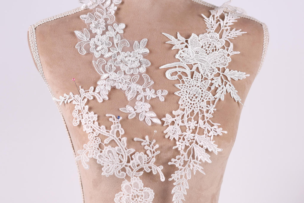 a close-up view of a back, with intricate white lace designs covering the back area. The lace appears to be a decorative element, possibly for a wedding dress or other formal attire.