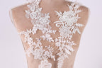 a close-up view of a back, with intricate white lace designs covering the back area. The lace appears to be a decorative element, possibly for a wedding dress or other formal attire.