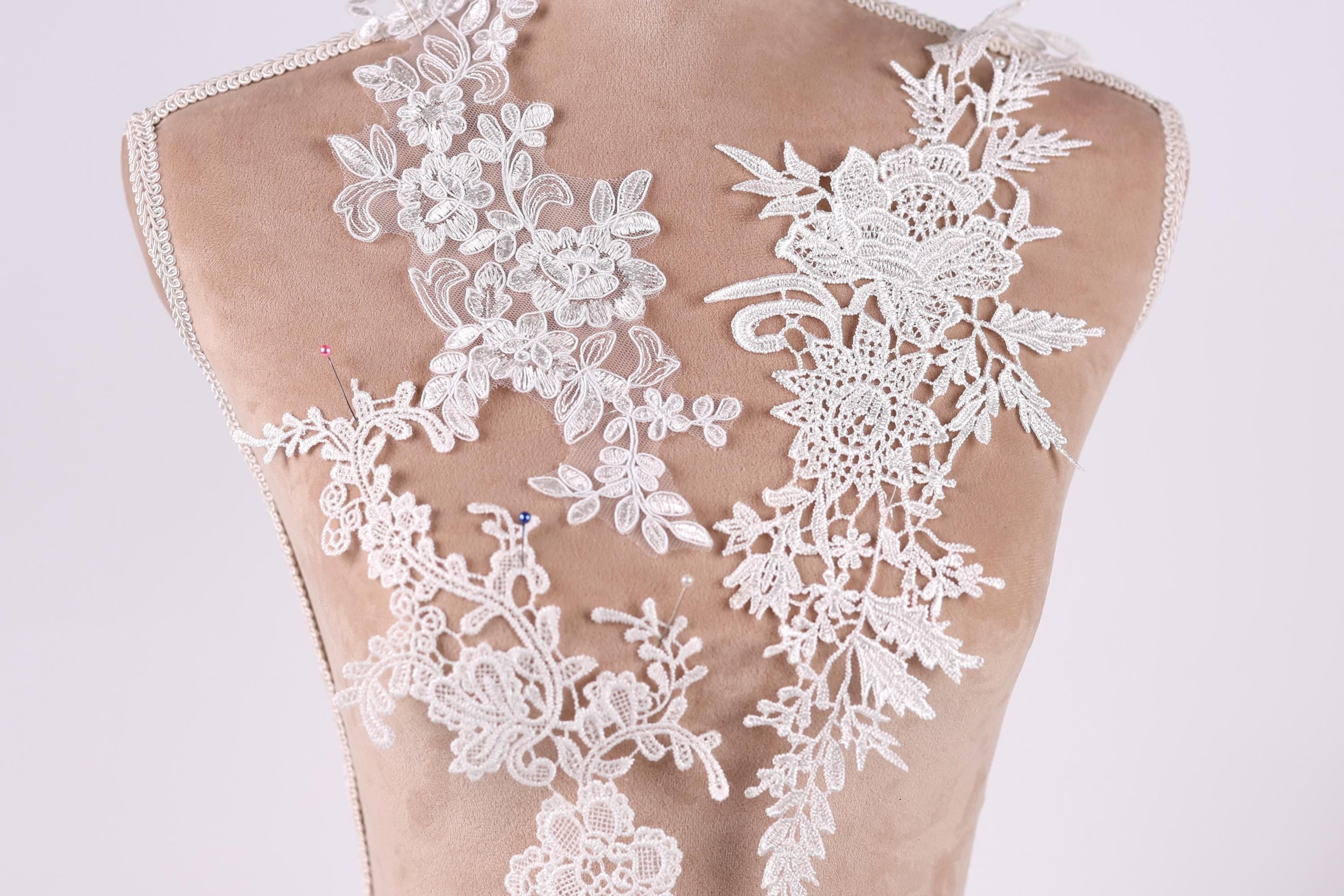a close-up view of a back, with intricate white lace designs covering the back area. The lace appears to be a decorative element, possibly for a wedding dress or other formal attire.