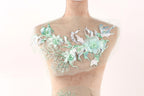 A mannequin with a floral design on its bust, featuring a variety of green and white flowers and leaves.