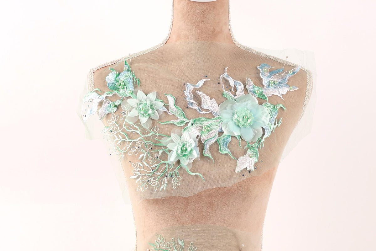 A mannequin with a floral design on its bust, featuring a variety of green and white flowers and leaves.