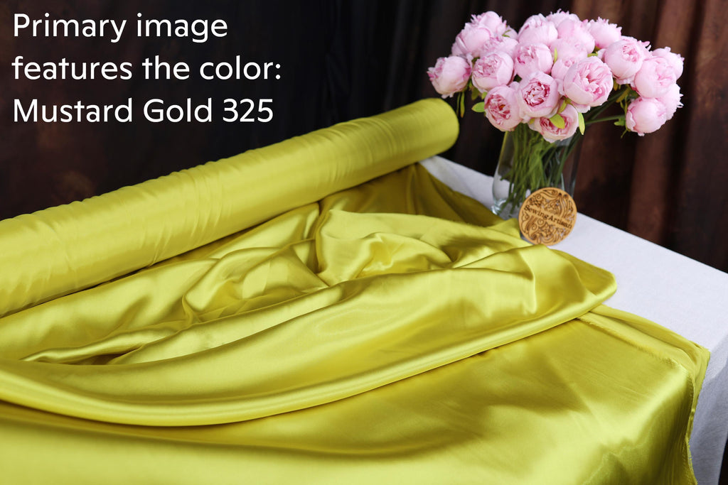 a yellow fabric with the text "Mustard Gold 325" and a vase of pink flowers on a table.