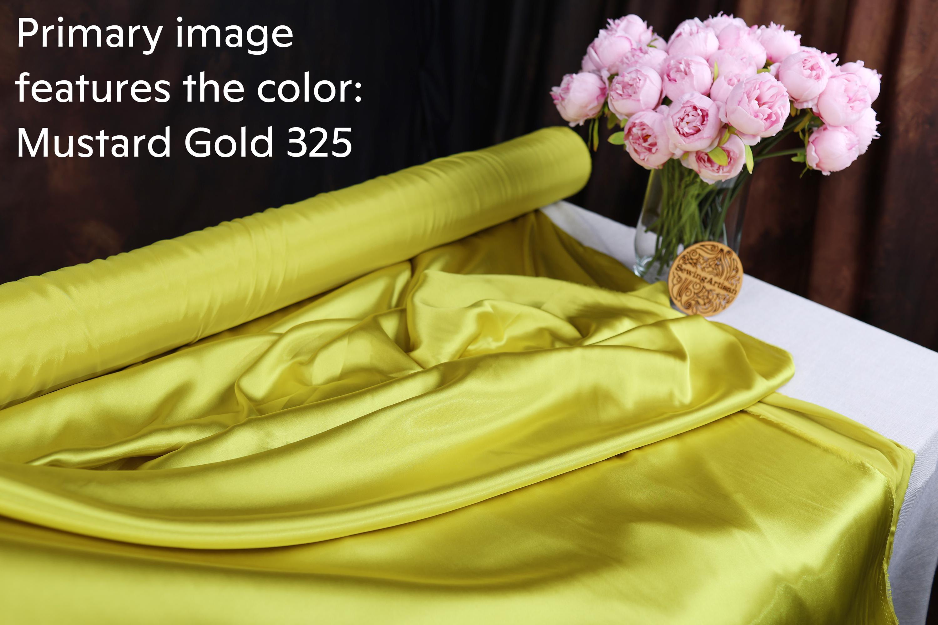 a yellow fabric with the text "Mustard Gold 325" and a vase of pink flowers on a table.