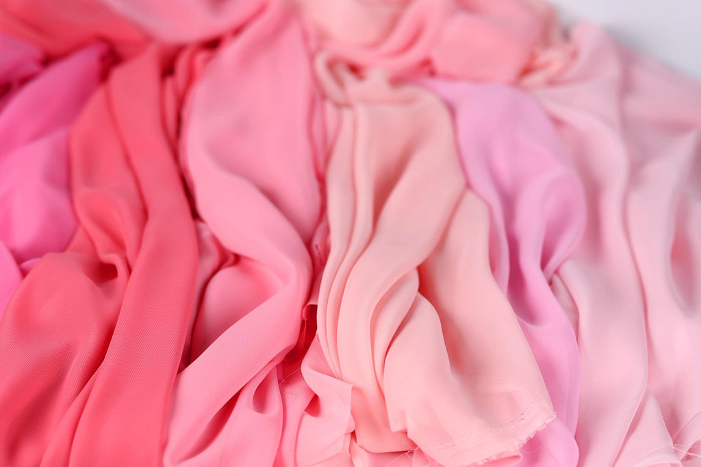 a close-up view of various pink and peach-colored fabrics, with the focus on the soft, flowing textures of the fabric.