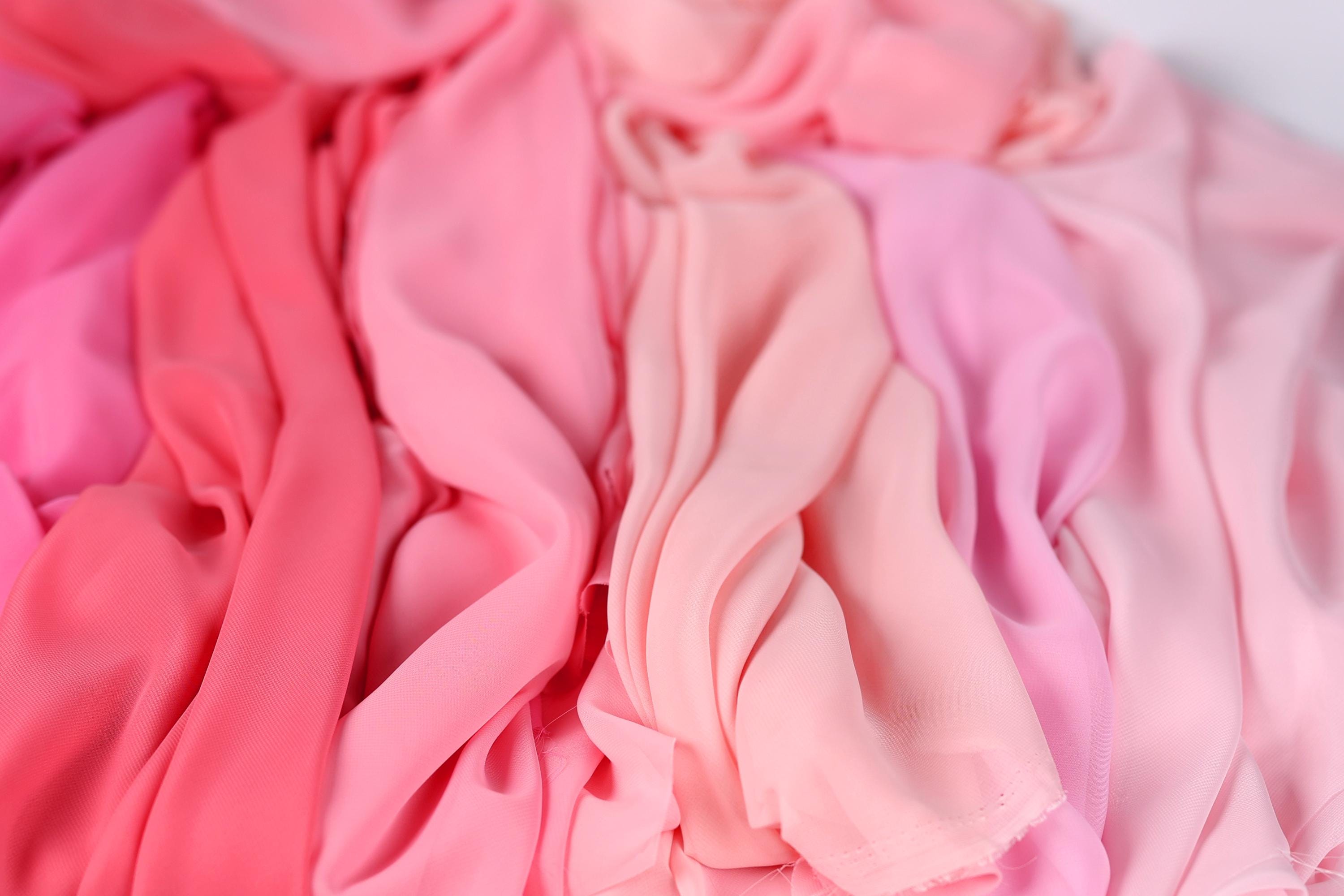 a close-up view of various pink and peach-colored fabrics, with the focus on the soft, flowing textures of the fabric.