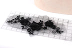 a transparent lace piece with black floral designs, placed on a ruler for scale.